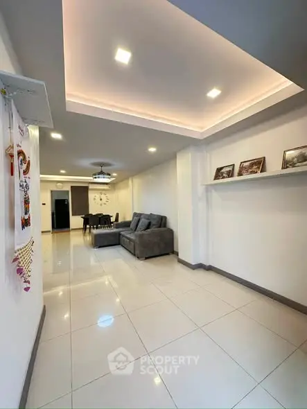 Spacious modern living room with elegant lighting and sleek tile flooring, perfect for family gatherings.