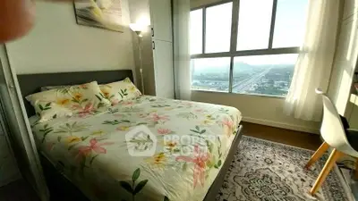 Bright bedroom with floral bedding and large windows offering scenic views.