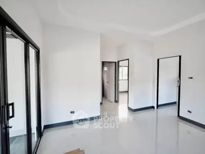 Spacious modern interior with sleek black-framed glass doors and pristine white walls.