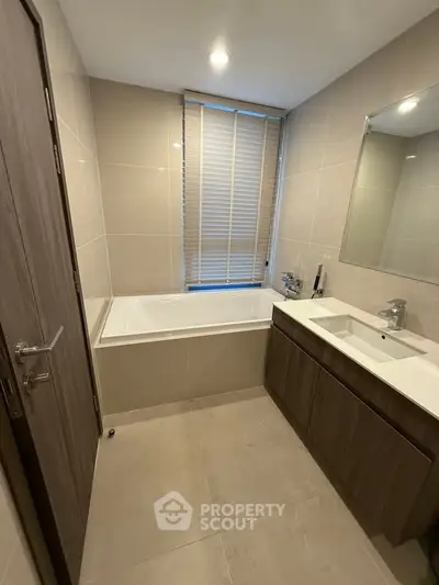 Modern bathroom with sleek design, featuring a bathtub and stylish vanity in a contemporary apartment.