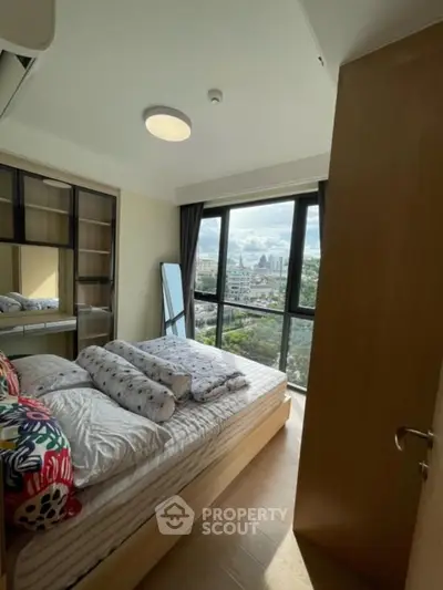 Cozy bedroom with large windows offering stunning city views, modern furnishings, and ample natural light.