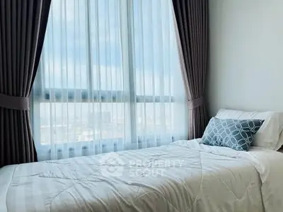 Cozy bedroom with large window and elegant curtains offering natural light and city view.