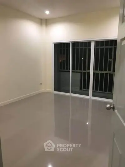 Spacious empty room with sliding glass doors leading to a balcony, perfect for customization.