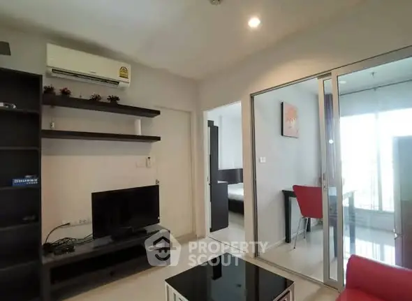 Modern living room with sleek furniture and open view to bedroom