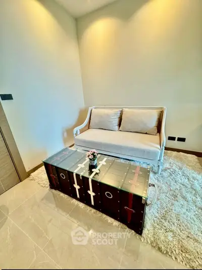 Chic living room with modern sofa and unique glass-top coffee table on plush rug.