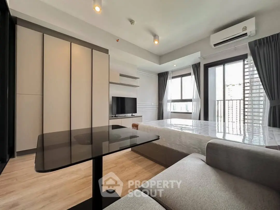 Modern studio apartment with sleek design, featuring a cozy living area and large windows for natural light.