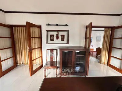 Elegant living room with wooden furniture and glass doors, showcasing a classic interior design.