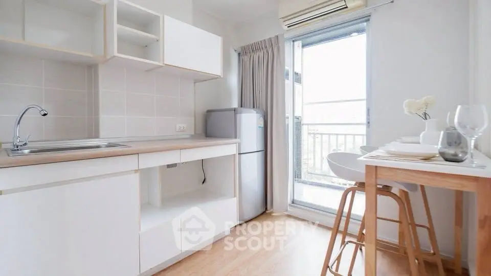 Bright modern kitchen with open layout and balcony access, featuring sleek cabinetry and dining area.