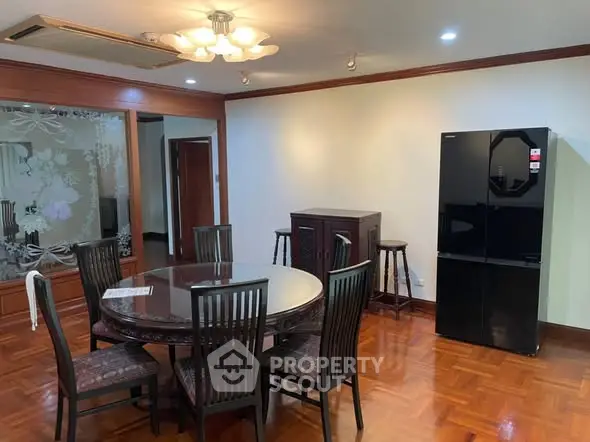 Spacious dining area with elegant round table and modern refrigerator in a stylish apartment.