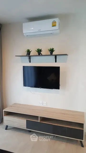 Modern living room with wall-mounted TV, air conditioner, and stylish shelf decor.