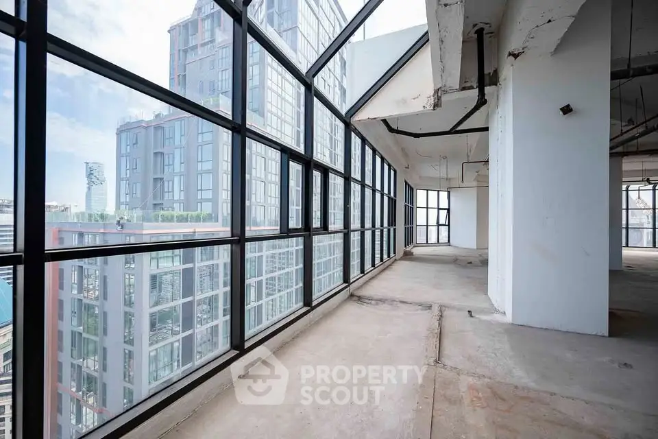 Spacious corner unit with floor-to-ceiling windows offering panoramic city views in a modern high-rise building.