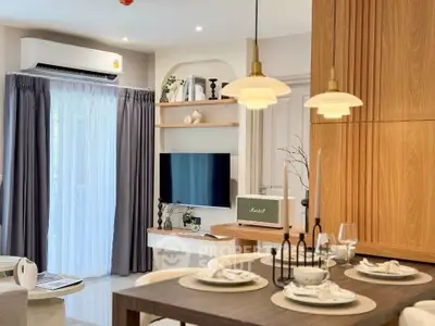 Modern living room with stylish decor and dining area, featuring a wall-mounted TV and elegant lighting.