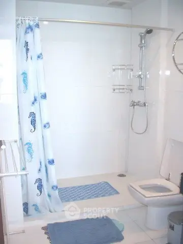 Modern bathroom with shower and seahorse-themed curtain in a bright, white-tiled space.