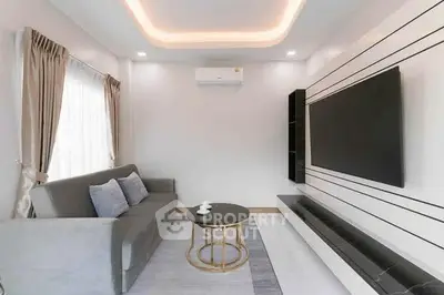 Modern living room with sleek design, featuring a large TV and stylish furniture.