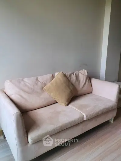 Inviting plush beige sofa in a modern living room with neutral walls and sleek hardwood flooring, perfect for cozy relaxation.
