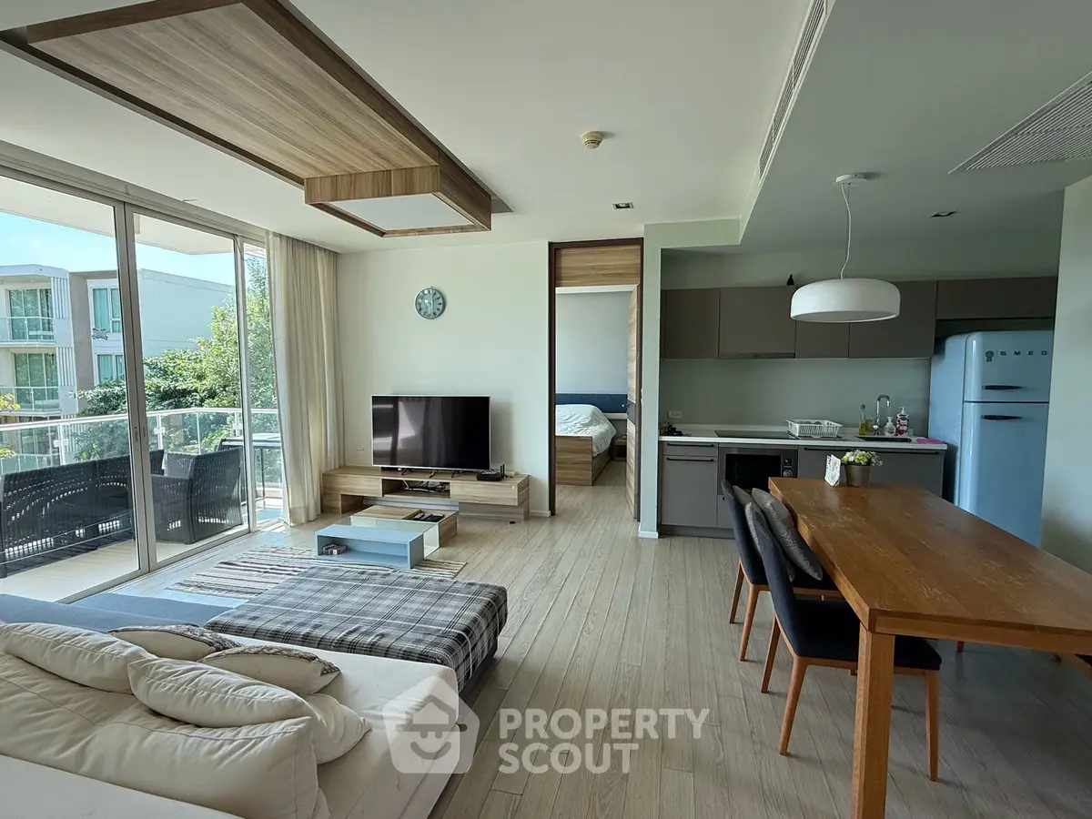 Modern open-plan living room with balcony and stylish kitchen in a bright apartment.