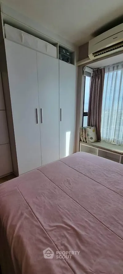 Cozy bedroom with natural light, featuring a built-in wardrobe and air conditioning.