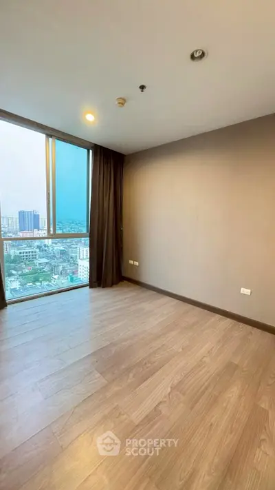 Spacious empty room with large window offering stunning city view