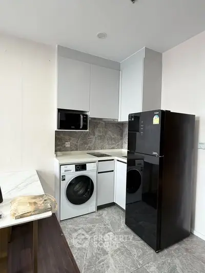 Modern kitchen with sleek appliances and marble backsplash in a compact layout.