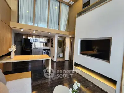 Modern living room with high ceilings and open layout, featuring a sleek TV wall and elegant decor.