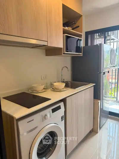 Modern kitchen with washing machine, fridge, and open layout in stylish apartment.