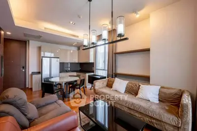 Modern living room with open kitchen, stylish lighting, and cozy seating area in a contemporary apartment.