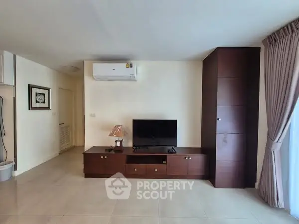 Spacious living room with modern TV unit and air conditioning, perfect for relaxation.