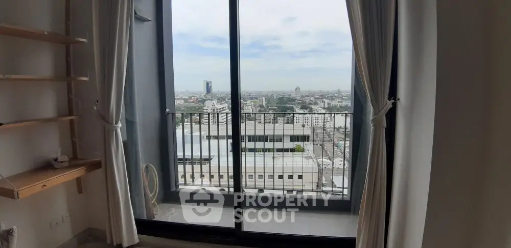 Stunning city view from modern apartment balcony with floor-to-ceiling windows.