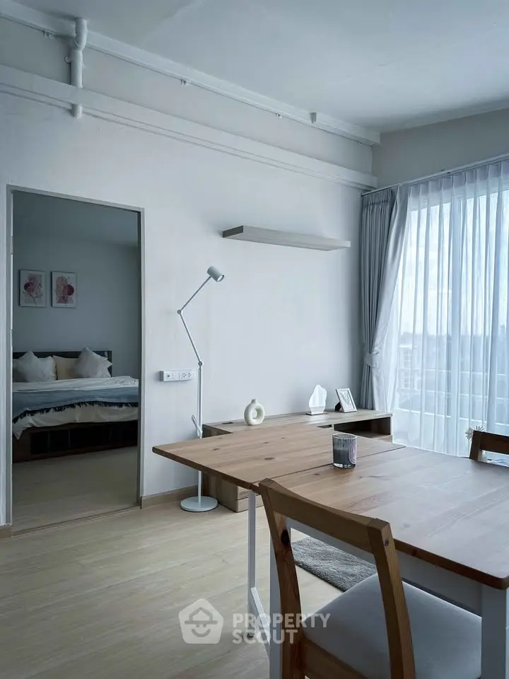 Modern dining area with natural light and view into cozy bedroom