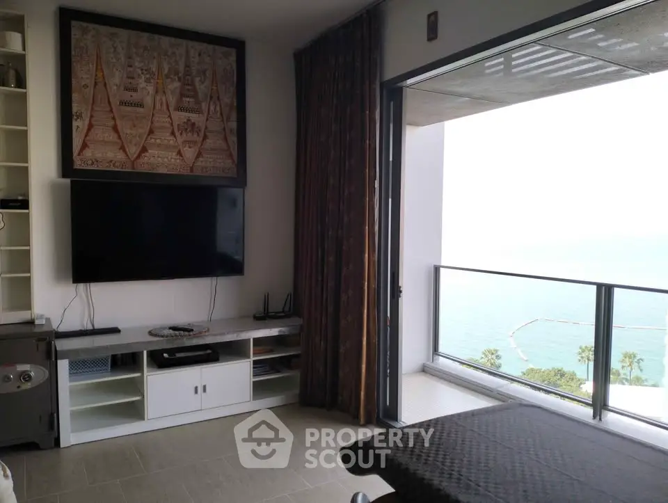 Modern living room with ocean view balcony, stylish decor, and wall-mounted TV.