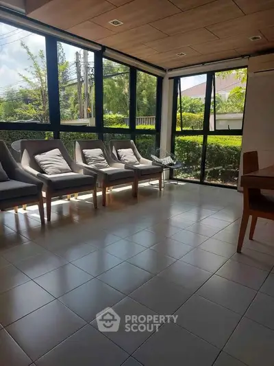 Spacious sunlit room with large windows and modern seating, perfect for relaxation or meetings.