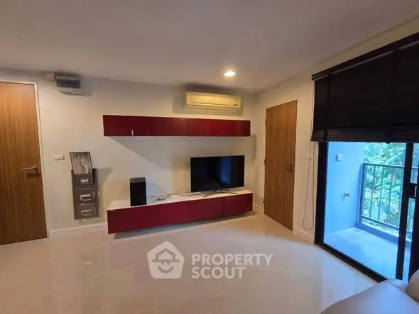 Modern living room with sleek TV unit and balcony access in stylish apartment.