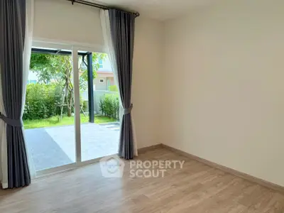 Spacious room with sliding glass doors opening to a lush garden view, perfect for natural light lovers.