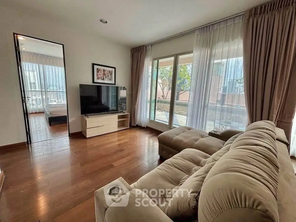 Spacious living room with plush sofa and large windows offering natural light and garden view.
