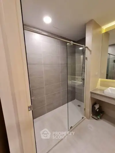 Modern bathroom with glass shower enclosure and sleek vanity in contemporary apartment.
