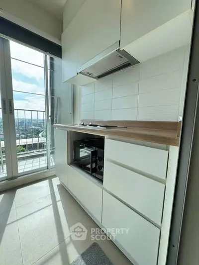 Modern kitchen with sleek cabinetry and city view from balcony