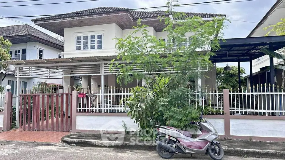 Charming two-story house with gated entrance and lush greenery in a serene neighborhood.