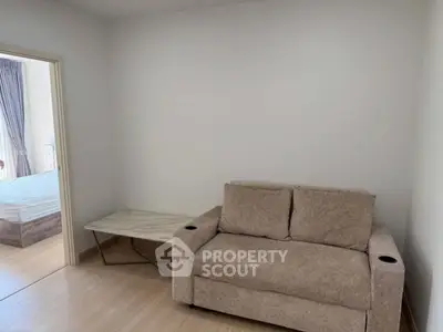 Cozy living room with beige sofa and marble side table, adjacent to a bedroom.