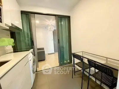 Modern kitchen with glass dining table and washing machine, open layout design.