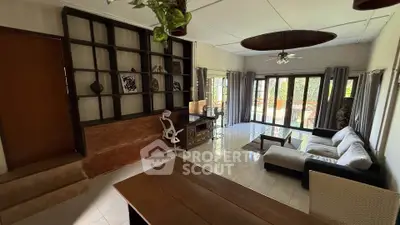 Spacious living room with modern decor and large windows opening to a lush garden view.