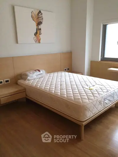 Modern bedroom with stylish decor and natural light, featuring a comfortable bed and wooden flooring.