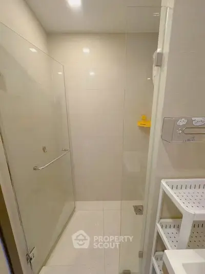 Modern bathroom with glass shower enclosure and sleek storage shelves.