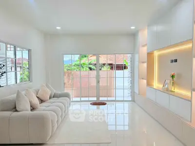 Bright modern living room with plush sofa and built-in shelving, large windows offer natural light.