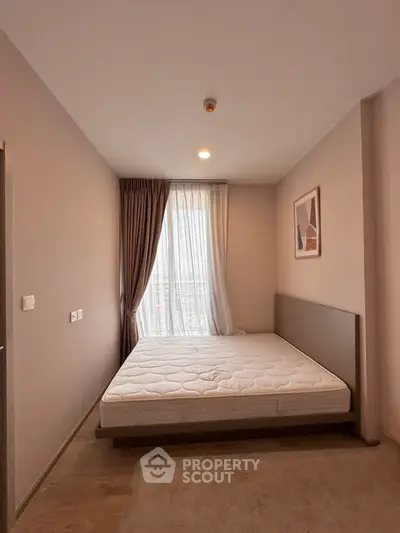 Modern bedroom with minimalist design and large window offering natural light.