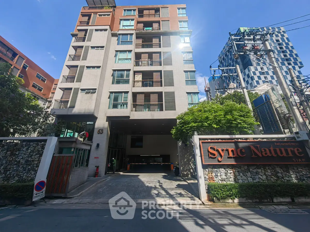 Modern urban apartment building with stylish facade and gated entrance in vibrant city setting.