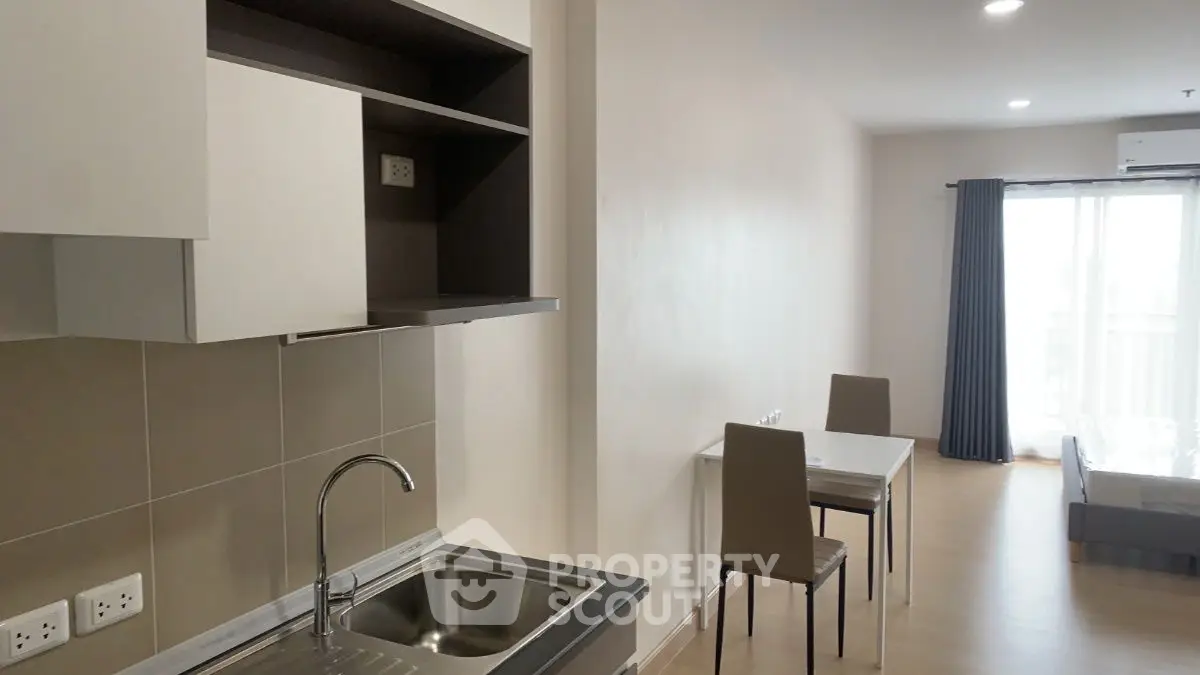 Modern studio apartment with open kitchen and dining area, featuring sleek cabinetry and natural light.