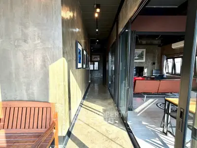 Modern industrial-style hallway leading to a spacious living area with large windows and contemporary decor.