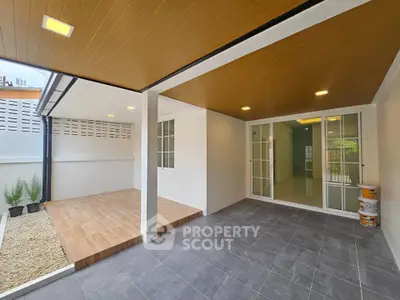 Modern covered patio with wooden deck and sliding glass doors, perfect for outdoor relaxation.