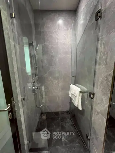 Luxurious marble bathroom with glass shower enclosure and modern fixtures.