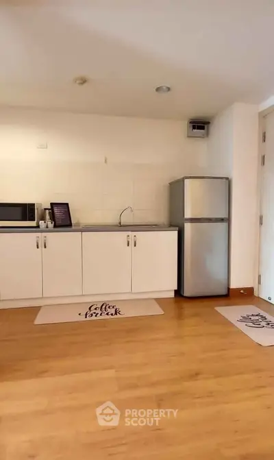 Modern kitchen with sleek cabinets and stainless steel fridge in cozy apartment.